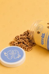 QERAT caramelized walnuts spilling out of tipped jar showing texture