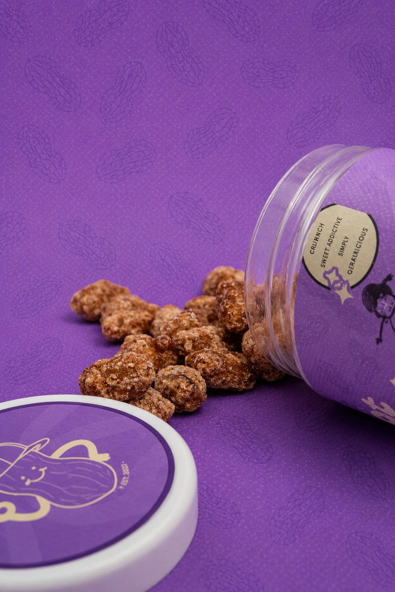 QERAT caramelized peanuts spilling out of tipped jar showing texture